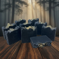 Multiple The Woodsman handmade cold process soap bars with gold glitter tops arranged in a moody forest setting